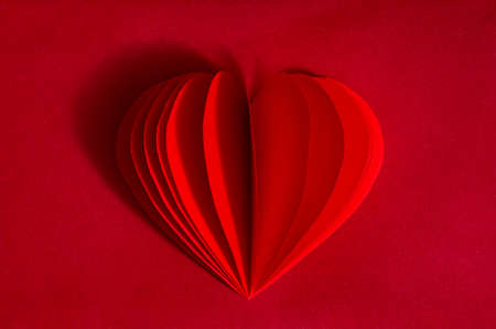 Red heart made of paper on burgundy paper. The concept of minimalism, romance, love, happiness. Monochromeの写真素材