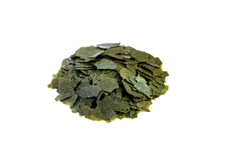 Dry handful, bunch green flakes compound fish feed flakes on White background. Side view