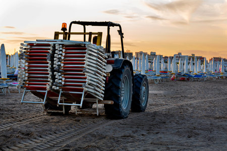 The tractor carries the sun loungers removed from the beach in the eveningの写真素材