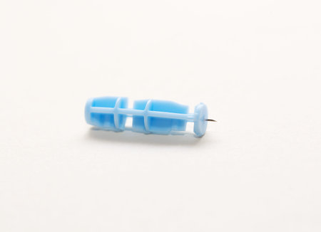 Close-up of a disposable sterile blood sampling lancet isolated on a beige background.