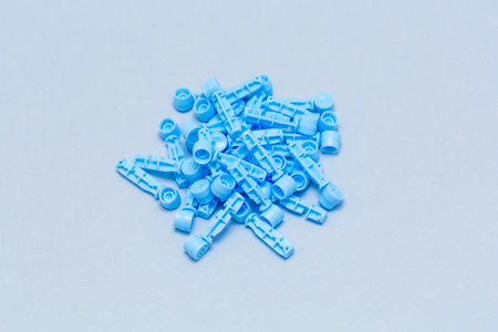 Disposable Sterile blood sugar testing lancets with protective cap isolated blue background, sterile medical devices taken from above, diabetes management or home blood testing concept. from aboveの写真素材