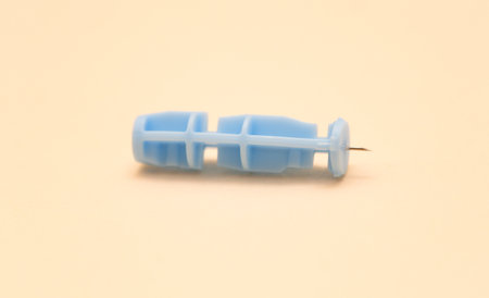 Close-up of a disposable sterile blood sampling lancet isolated on a beige background.の写真素材