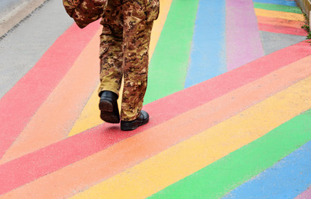 Individual in camouflage pants walks on colorful pathway, featuring bright stripes of paint, creating a lively urban atmosphere and promoting inclusivityの写真素材