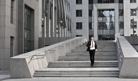 Handsome businessman standing on stairs of business centerの写真素材