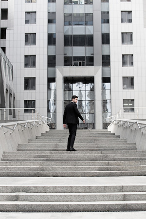 Handsome businessman standing on stairs of business centerの写真素材