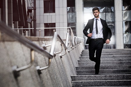 Handsome businessman standing on stairs of business centerの写真素材