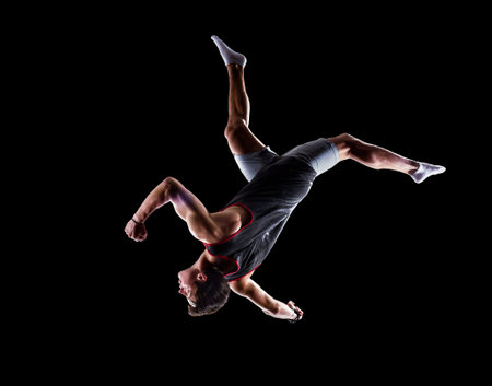 Isolated on black young man is jumping  the trampoline