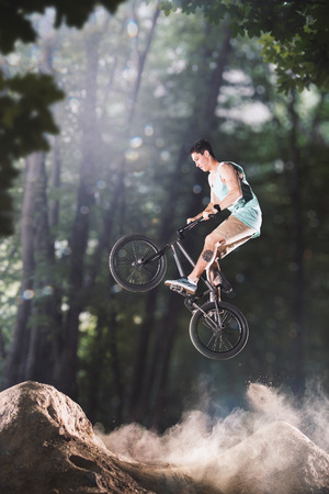 bmx bicycle rider tricking on the forest hillsの写真素材