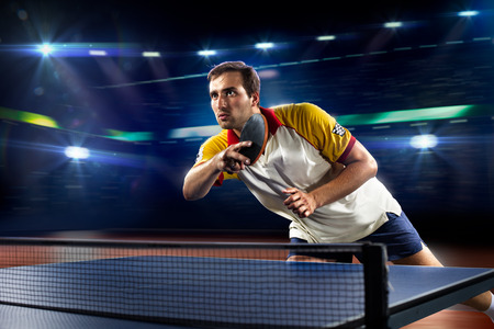 young sports man tennis player is playing on black background with lightsの写真素材