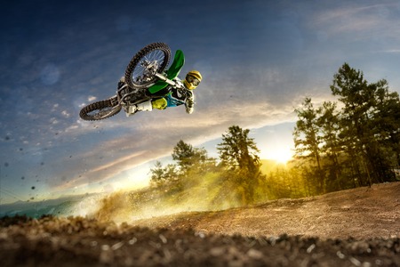 Dirt bike rider is flying high in eveningの写真素材
