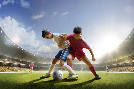 Childrens are playing soccer on grand arena in sunlightsの写真素材