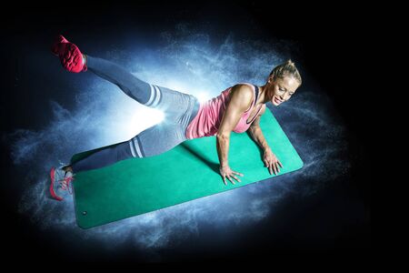 Sporty woman with beautiful beautiful body working out on black backgroundの写真素材