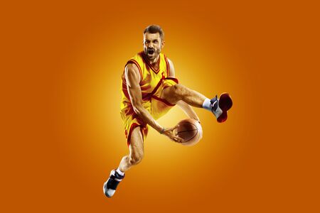 bright professional basketball player on the orange backgroundの写真素材