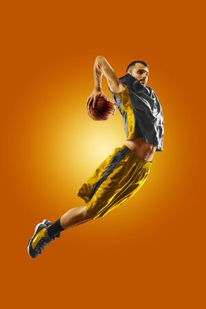 bright professional basketball player on the orange backgroundの写真素材