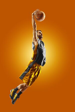 bright professional basketball player on the orange backgroundの写真素材