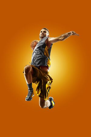 bright professional basketball player on an orange backgroundの写真素材