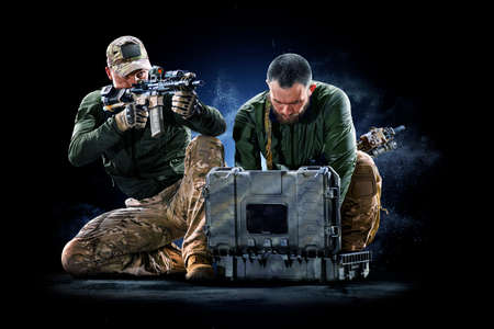 Army soldiers in Protective Combat Uniform holding Special Operations Forces Combat Assault Rifle on dark backgroundの写真素材