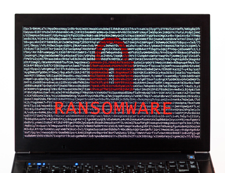 Ransomware text with red lock over encrypted text on a laptop screen against a white background - cyber crimeの写真素材