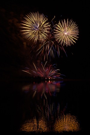 Fireworks of many colors on  display and refelcting in a lakeの写真素材