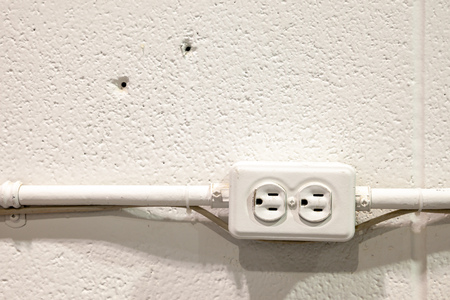 Old rustic North American electrical outlet on a white brick wallの写真素材