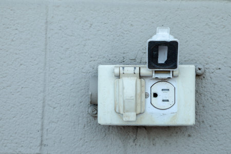 Old rustic North American electrical outlet on a exterior grey brick wall