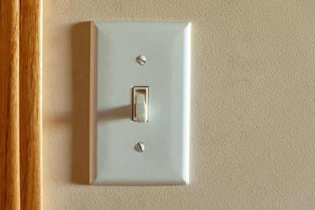 An old North American light switch on a wall near a doorwayの写真素材