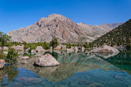 Majestic blue mountain lake with large stone in Tajikistanの写真素材