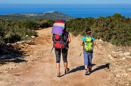 A family with large backpacks are on the sandy road to the seaの写真素材