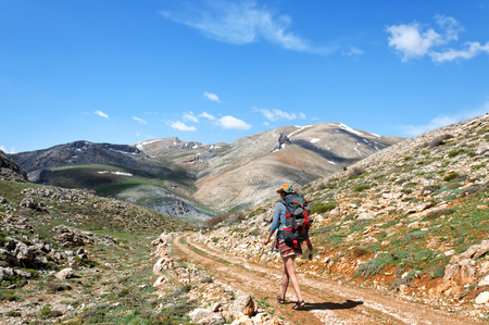 backpacker with backpack walking on dirt road in Mountains, southern Turkeyの写真素材