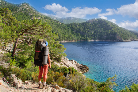 man with a backpack stands on the shore of the Mediterranean Sea and looks into the distanceの写真素材