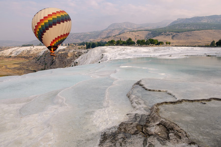 Pamukkale, Turkey : Hot air balloon flying over Travertine pools limestone terraces on a beautiful dayの写真素材