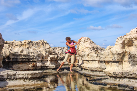 happy mother with small child in a sling are walking along the sharp coral coast of the Mediterranean Seaの写真素材