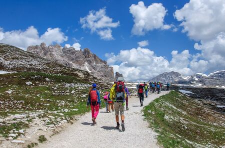 a group of tourists is walking along a wide trail in the Dolomites, Italyの写真素材