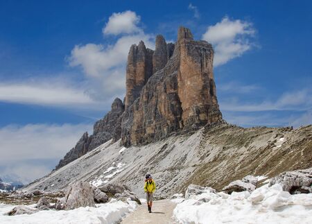 Dad with small child in a backpack walks along snow-covered dolomites, Italy.の写真素材