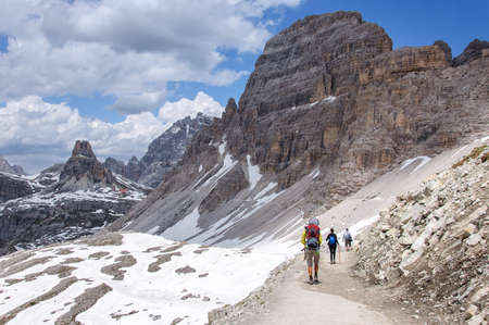 a group of tourists is walking along a wide trail in the Dolomites, Italyの写真素材