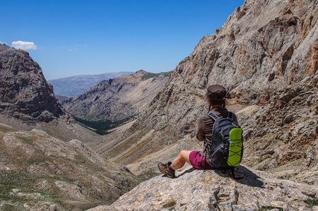 A sporty woman with a backpack on her back watches high in the Aladaglar mountains. Turkeyの写真素材