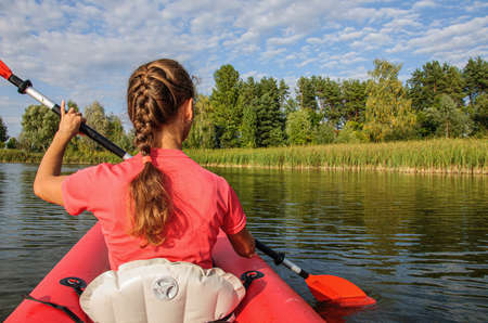 A young sports girl floats on the Zdwyzh River on a red kayak. Ukraineの写真素材