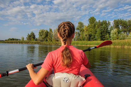 A young sports girl floats on the Zdwyzh River on a red kayak. Ukraineの写真素材