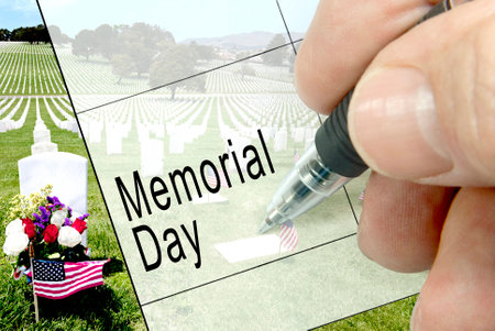 Pen-in-hand calendar notation of United States holiday, Memorial Day, American flag, floral display, and national cemetary in background.の写真素材