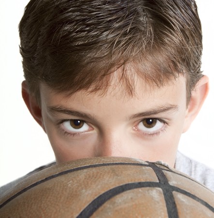 Young teen peering over the top of a basketball. Isolated on white.の写真素材