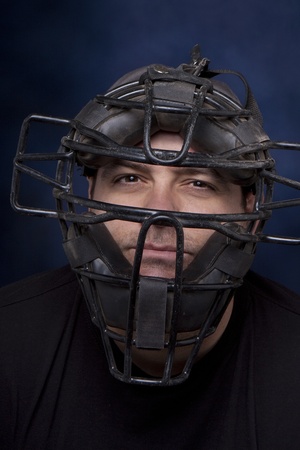 Thirty-something man in a catcher's mask with a dramatic blue background.の写真素材