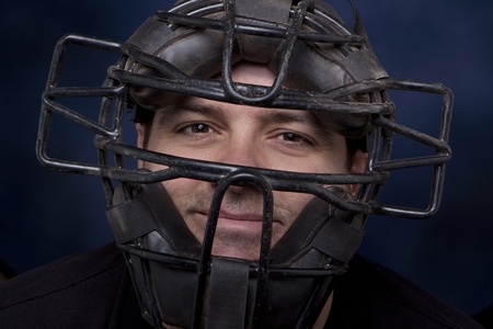 Thirty-something man in a catcher's mask with a dramatic blue background.の写真素材
