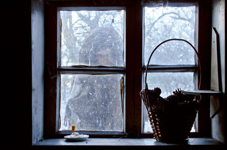 vague silhouette lost in the snow outside the window of a cozy houseの写真素材