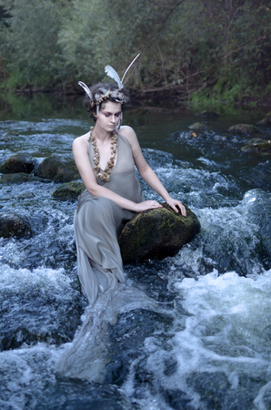 covering his eyes mermaid sitting on the rocks in the river, pretends to be a modest insidious evil, attracts travelers, then drown them will be in the cold fast flowing water, mermaids are all, preteの写真素材