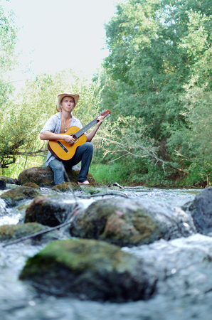 waterfall in the woods and a young man playing guitarの写真素材