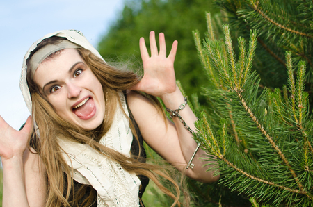 young witch sat under a pine tree and scares passers-by terrible face. are you afraid of her wild grin full of merry madness?の写真素材