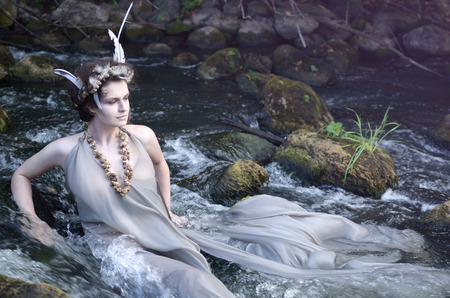 river nymph in a gray silk dress, a necklace of sea snail shells and a headdress of perevsidit and resting in his riverの写真素材
