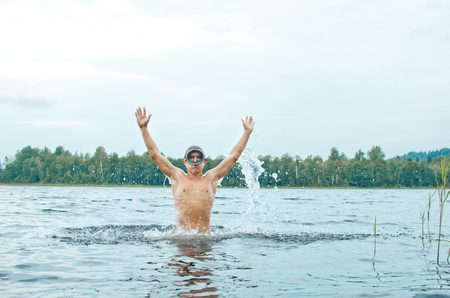man in a diver mask jumps out of the water producing a lot of sprayの写真素材