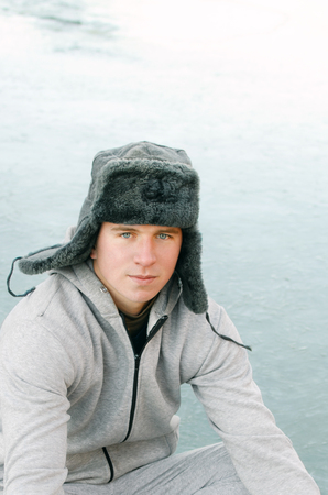 winter portrait of a young man in a fur hat with earflapsの写真素材