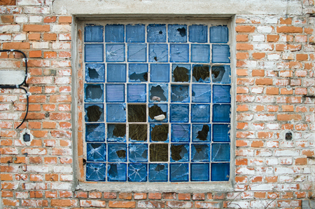 broken window with the remains of blue glass blocks in the old brick wallの写真素材